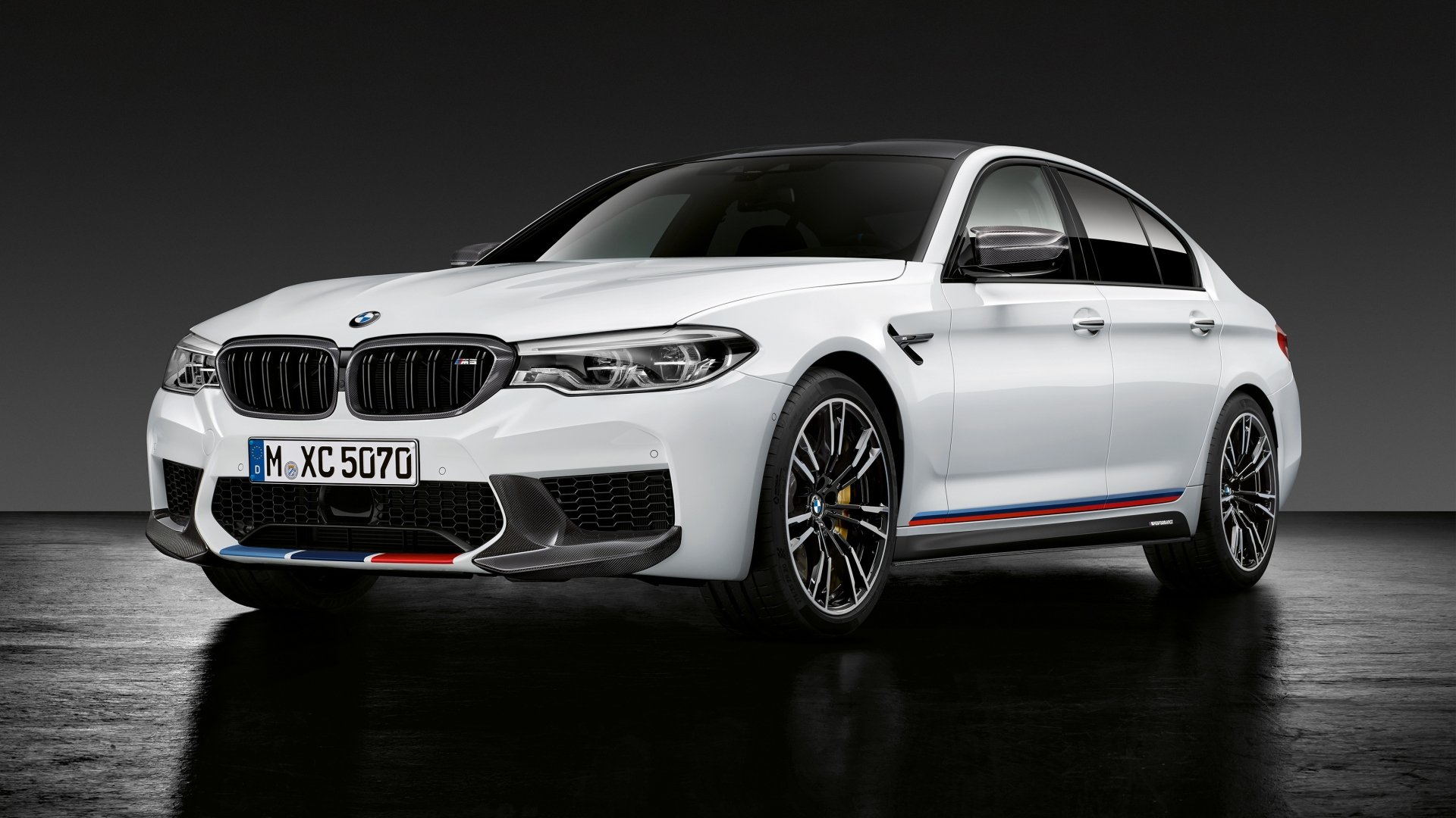 White BMW M5 sedan showcased on a dark background, highlighting its sleek design and sporty accents, captured in high-definition for a PC desktop wallpaper.