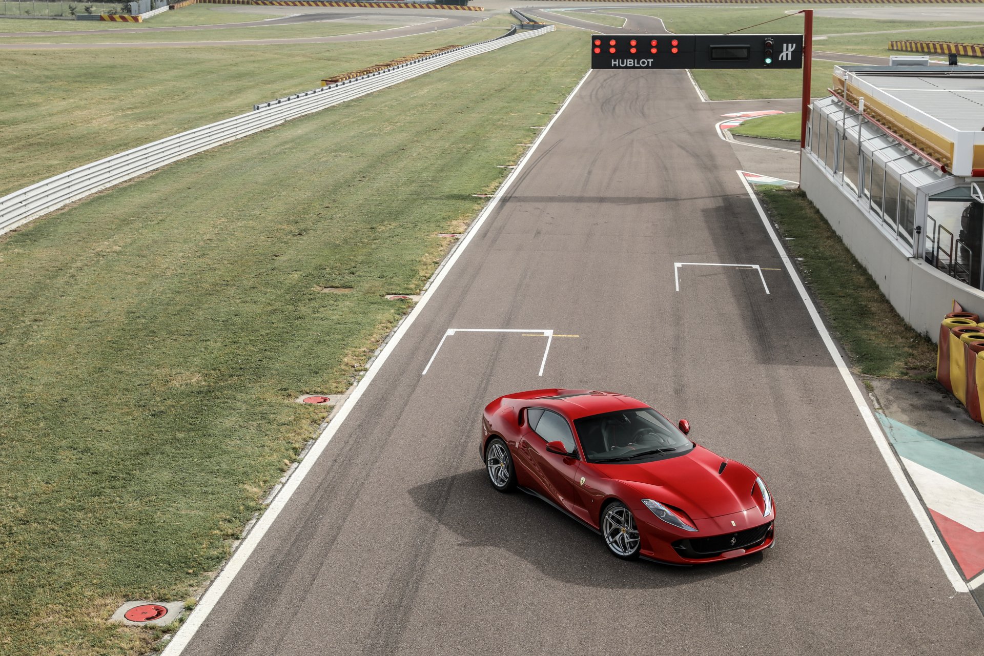 A red Ferrari 812 Superfast grand tourer parked on a racetrack, captured in sharp 4K Ultra HD detail as a desktop wallpaper background.
