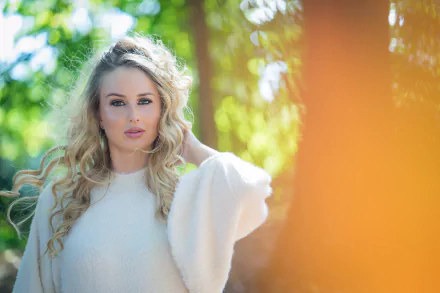 Blonde woman with green eyes posed thoughtfully in a soft, sunlit background, captured with depth of field in stunning 4K Ultra HD quality.