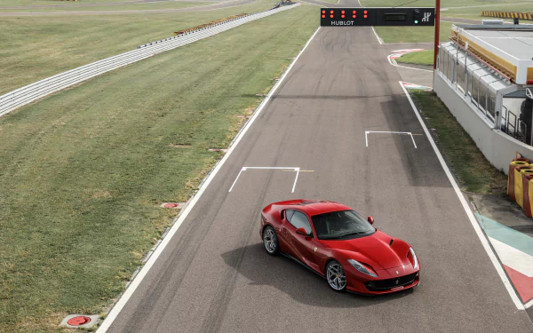 A red Ferrari 812 Superfast grand tourer parked on a racetrack, captured in sharp 4K Ultra HD detail as a desktop wallpaper background.