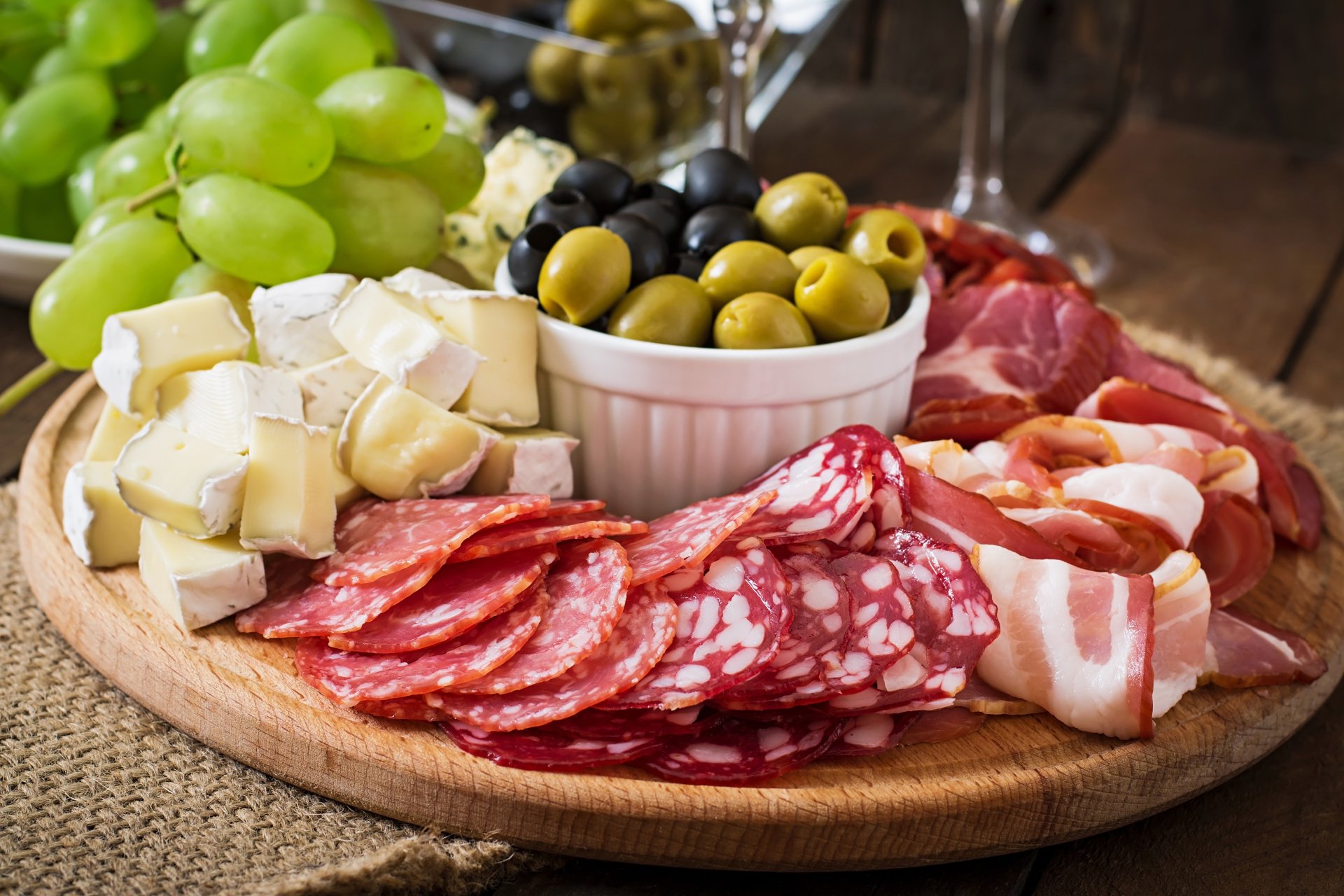 A 4K Ultra HD still life of a wooden platter with olives, green grapes, sliced cheese, and assorted cured meats, set as a PC desktop wallpaper and background.
