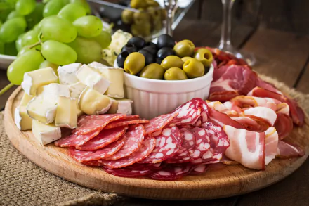 A 4K Ultra HD still life of a wooden platter with olives, green grapes, sliced cheese, and assorted cured meats, set as a PC desktop wallpaper and background.
