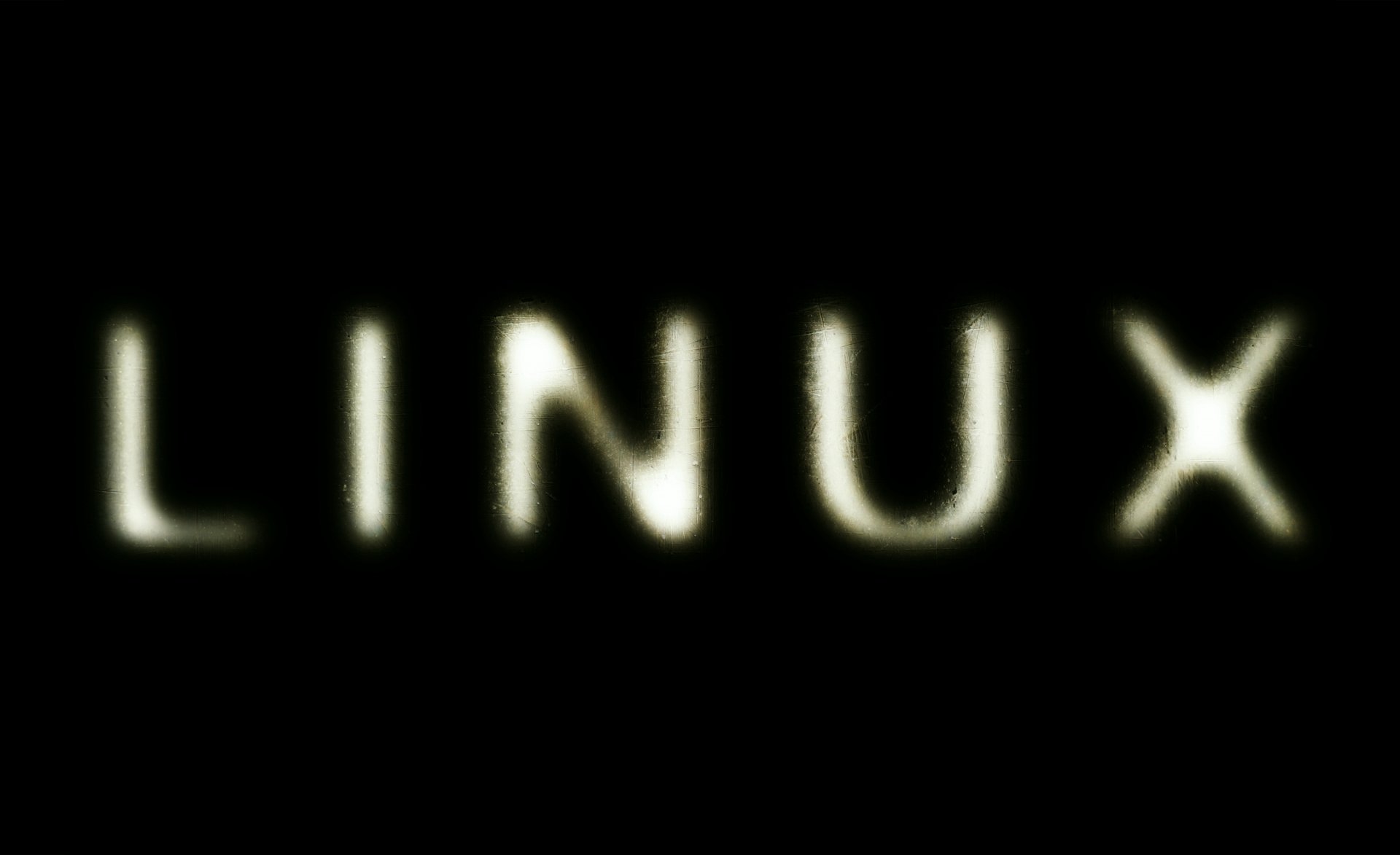 HD desktop wallpaper featuring the word LINUX illuminated against a black background, highlighting technology and open-source software themes.