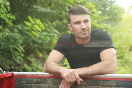 HD wallpaper of a contemplative man leaning on a red truck, surrounded by greenery.