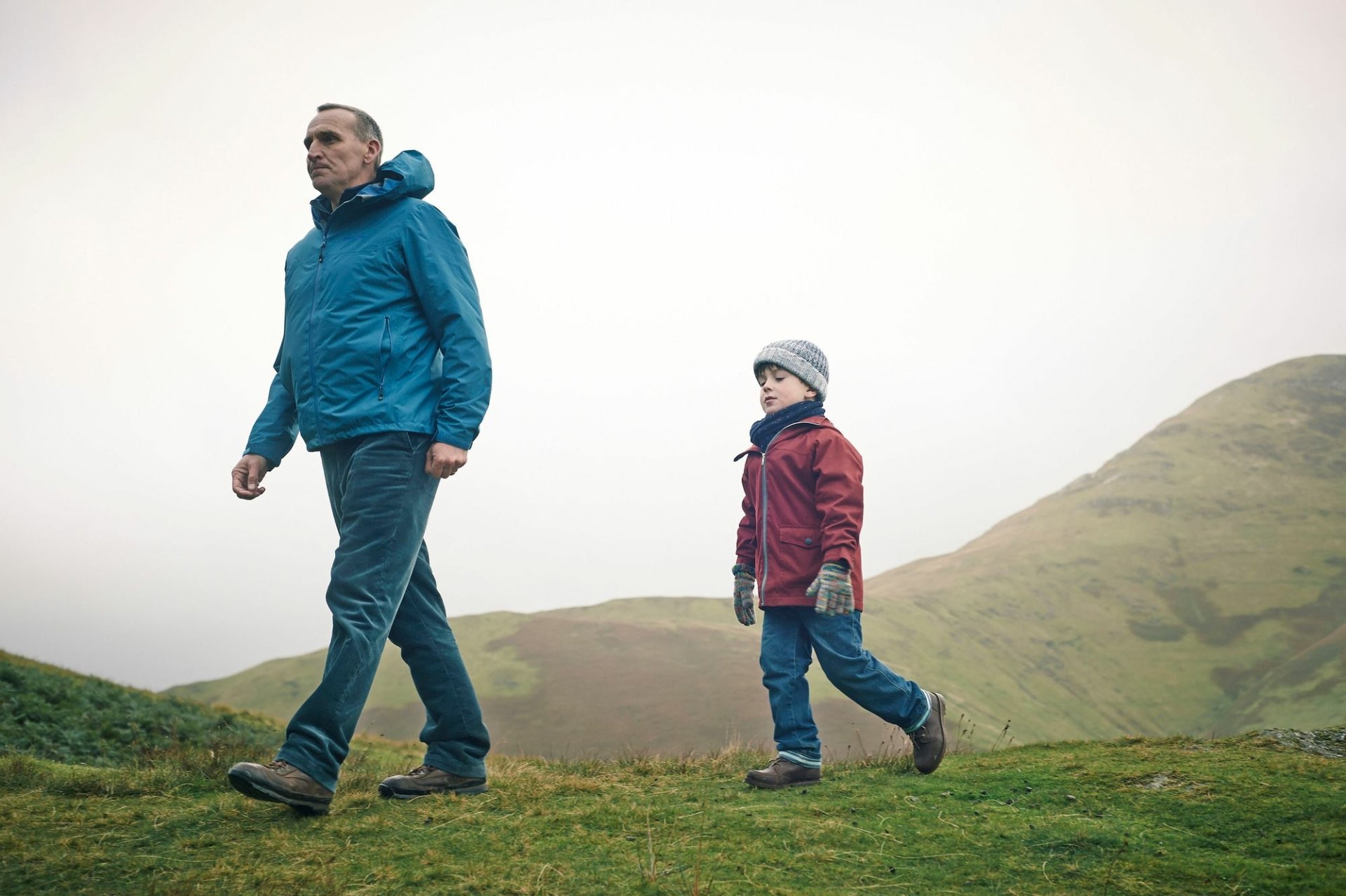 HD desktop wallpaper from The A Word featuring two characters walking in a green landscape.