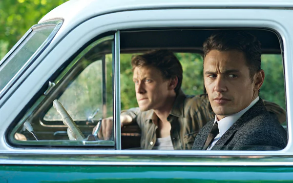 HD PC desktop wallpaper from TV show 11.22.63: two men seated in a vintage car seen through the open window, one looking at the camera, green car exterior and leafy background.