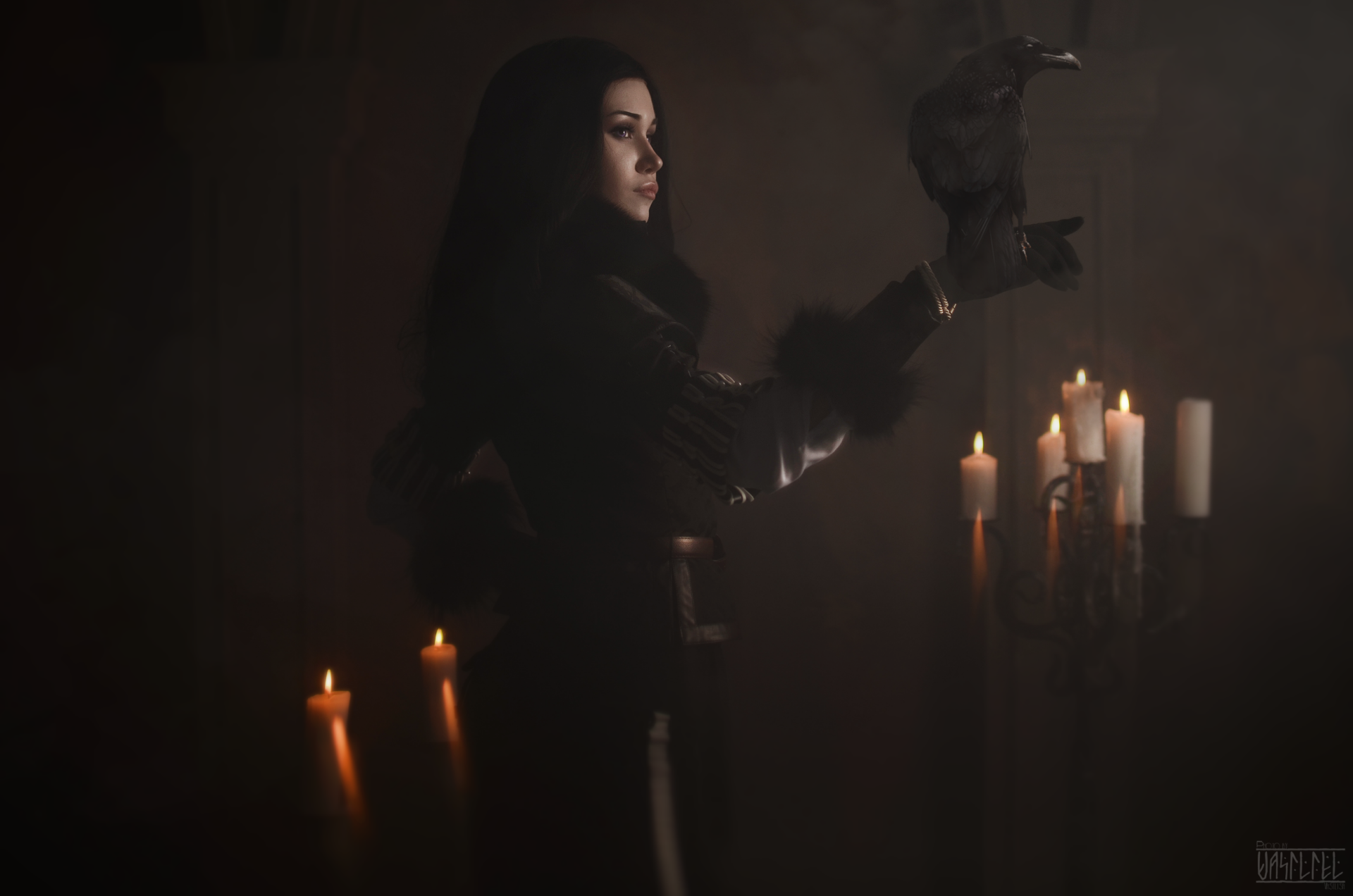 HD PC desktop wallpaper featuring a woman cosplaying as Yennefer of Vengerberg, holding a raven amid glowing candles in a dark, mystical setting.