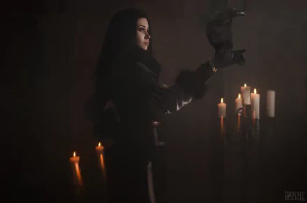 HD PC desktop wallpaper featuring a woman cosplaying as Yennefer of Vengerberg, holding a raven amid glowing candles in a dark, mystical setting.