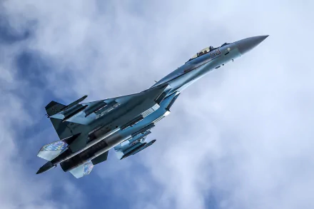 HD desktop wallpaper featuring a military Sukhoi Su-35 jet fighter warplane soaring against a cloudy sky.