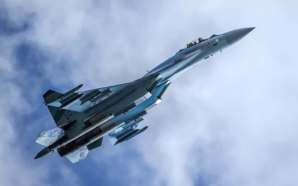 HD desktop wallpaper featuring a military Sukhoi Su-35 jet fighter warplane soaring against a cloudy sky.
