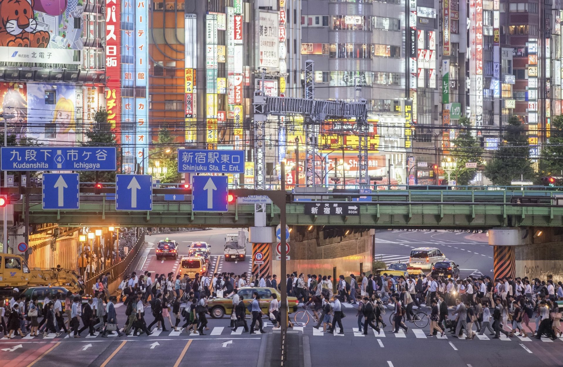 HD desktop wallpaper of bustling Shinjuku, Tokyo with vibrant city lights and a crowd crossing the street.