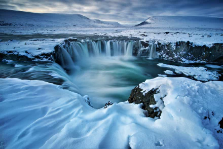 Winter landscape of Iceland’s Goðafoss waterfall surrounded by snow and ice, captured in stunning 4K Ultra HD for a breathtaking nature desktop wallpaper.