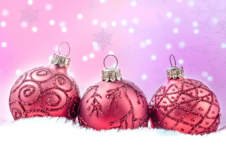 HD PC desktop wallpaper featuring three pink Christmas baubles with intricate designs, set against a soft pink holiday background with glowing light effects.
