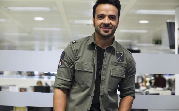 HD desktop wallpaper featuring a smiling man in a green shirt, in an office setting.