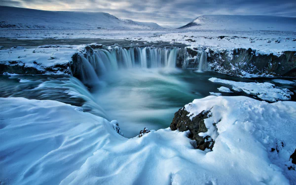 Winter landscape of Iceland’s Goðafoss waterfall surrounded by snow and ice, captured in stunning 4K Ultra HD for a breathtaking nature desktop wallpaper.