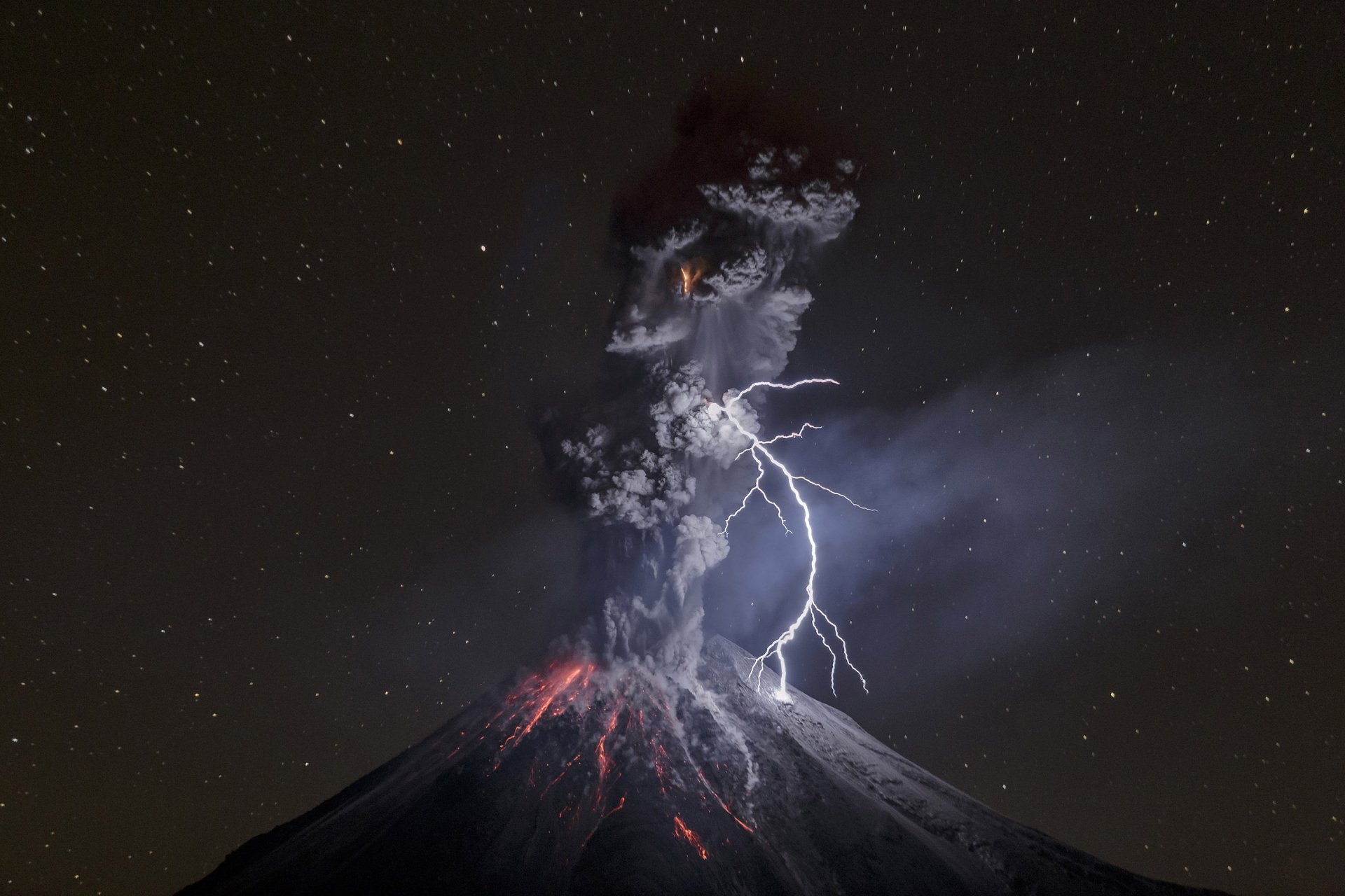 HD wallpaper of a nighttime volcanic eruption with lightning illuminating the smoke and red-hot lava against a backdrop of stars.