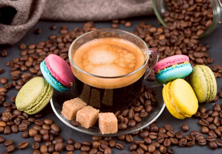 A 4K Ultra HD still life of a clear cup of coffee surrounded by colorful macarons, sugar cubes, and scattered coffee beans on a dark surface.