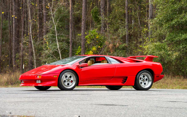 A red Lamborghini Diablo supercar parked on a road, surrounded by tall trees, captured in high definition for a PC desktop wallpaper and background.