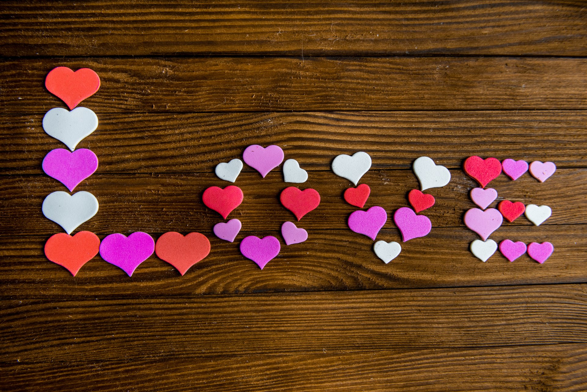 Artistic 4K Ultra HD desktop wallpaper featuring the word LOVE spelled out with colorful heart shapes on a wooden background.