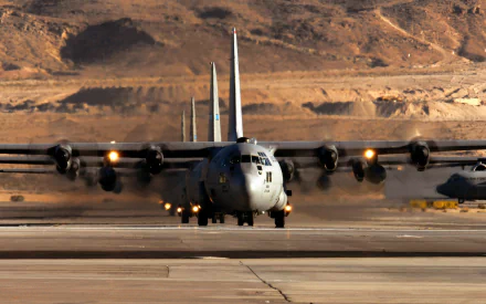 HD desktop wallpaper featuring a Lockheed C-130 Hercules military transport aircraft taxiing on a runway with desert terrain in the background.