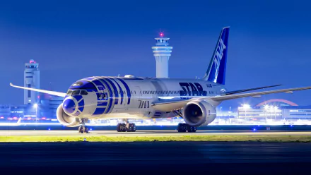 HD desktop wallpaper of a Boeing 787 Dreamliner at an airport, illuminated at night with control towers in the background.