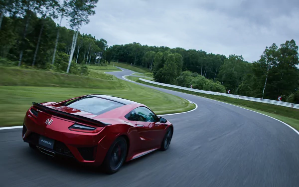 A red Honda NSX supercar speeds along a winding road surrounded by lush greenery, captured in a sharp 4K Ultra HD desktop wallpaper.