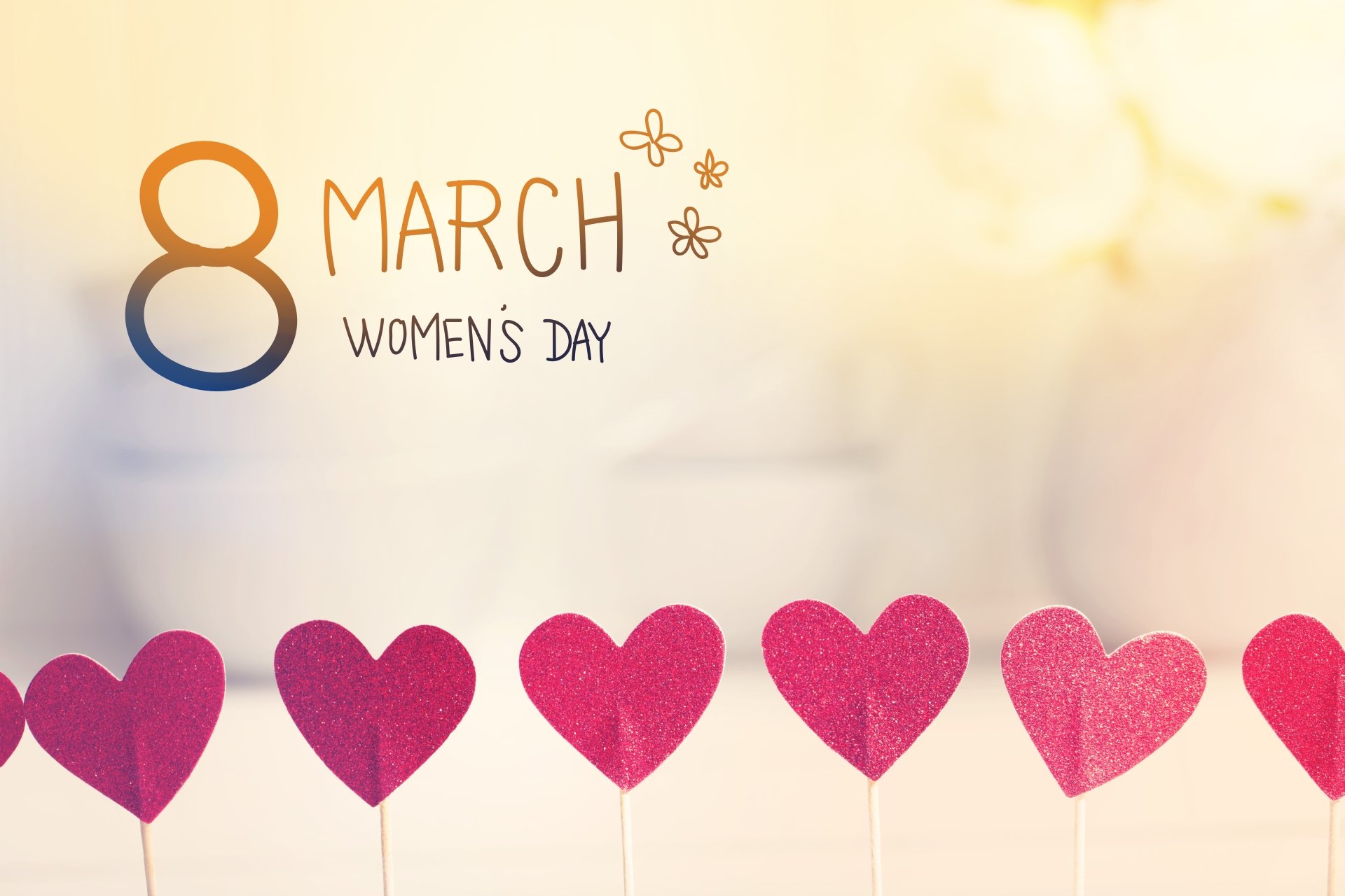 4K Ultra HD Women's Day wallpaper featuring a soft background with a row of red hearts and 8 March Women's Day text decorated with small flowers.
