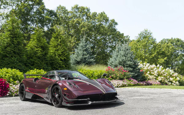 Maroon Pagani Huayra Roadster BC supercar parked on a driveway surrounded by gardens and trees — high-resolution 2K Quad HD PC desktop wallpaper of the Pagani Huayra vehicle.