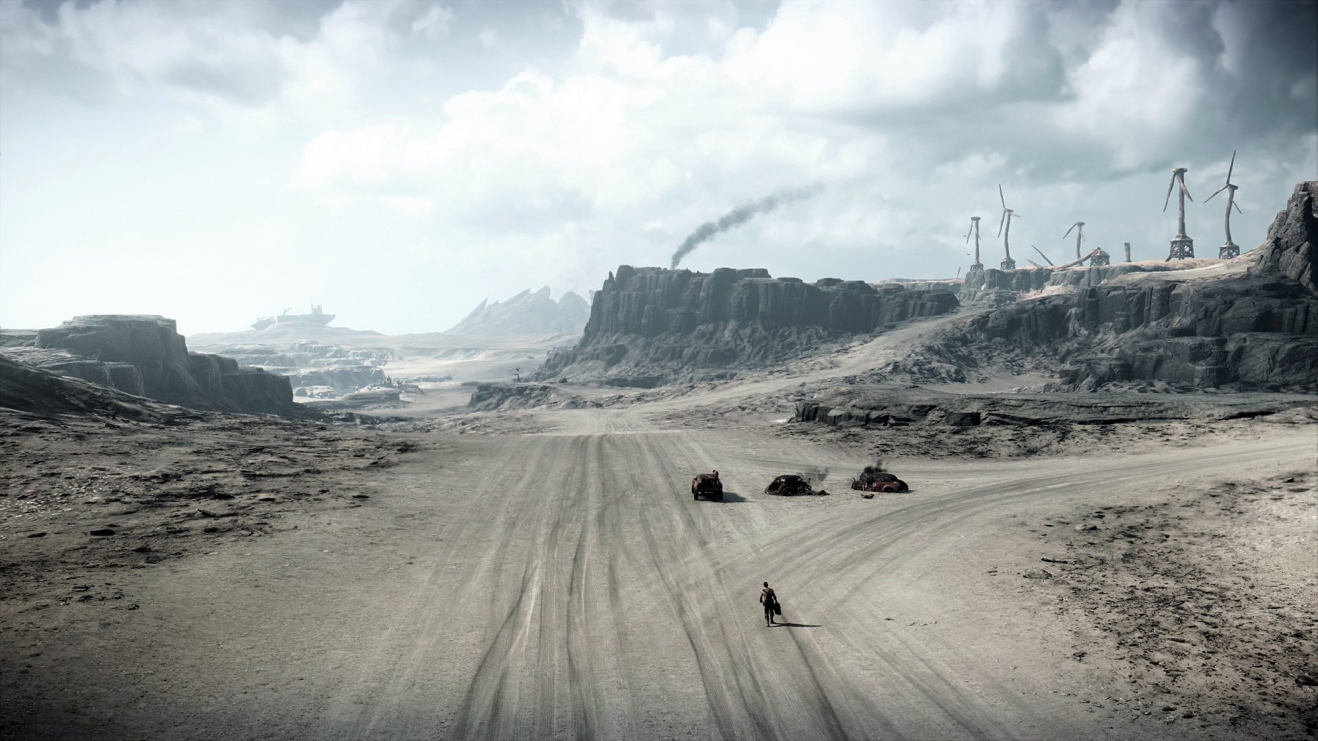 Mad Max video game 2K Quad HD PC desktop wallpaper: lone rider and three vehicles traverse a vast, windswept desert road toward cliffs and wind turbines beneath a stormy sky.