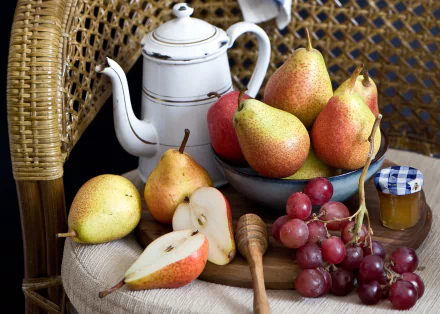 2K Quad HD PC desktop wallpaper still life: white teapot beside bowl of pears, sliced pear, red grapes, honey jar and dipper on woven chair — fruit-themed food background.