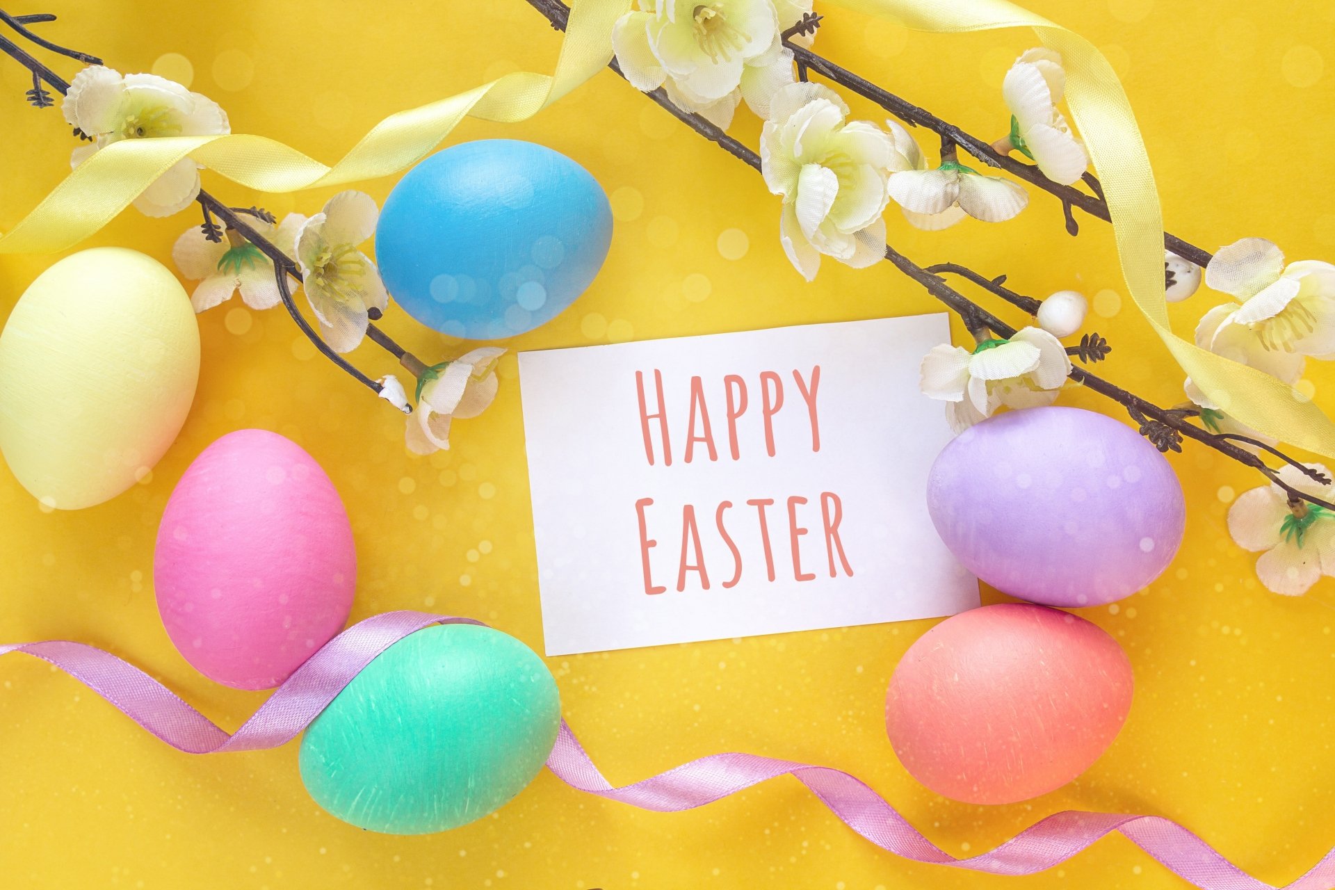 Brightly colored Easter eggs and spring blossoms surround a Happy Easter card, set against a vibrant yellow background in this HD PC desktop wallpaper.