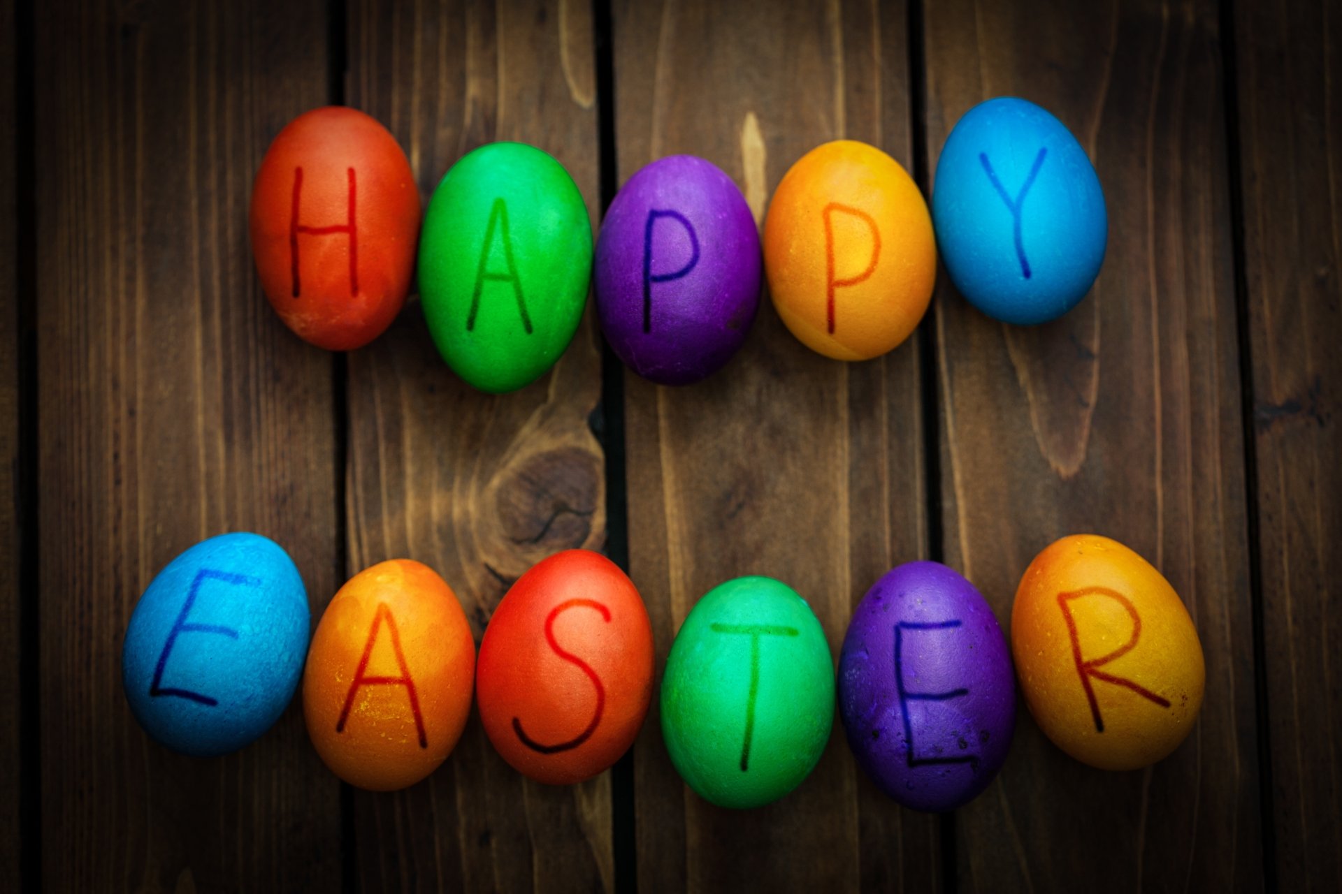 Colorful Easter eggs spelling out Happy Easter on a wooden background, vibrant and festive for a 4K Ultra HD holiday desktop wallpaper.