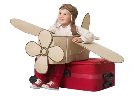 Smiling little boy in an aviator helmet peeks from a cardboard airplane atop a red suitcase — child photography, 4K Ultra HD PC desktop wallpaper background.