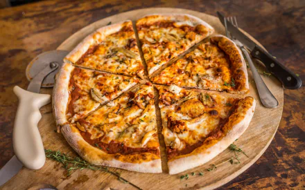 HD PC desktop wallpaper of a freshly sliced pizza on a wooden board with a knife and fork beside it, showcasing delicious melted cheese and herbs.
