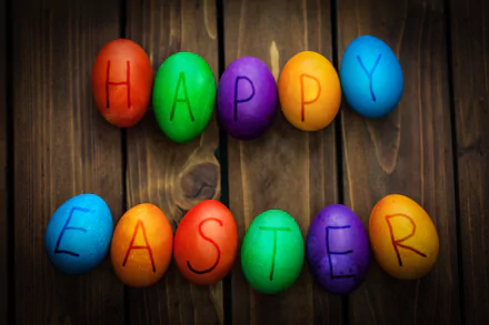 Colorful Easter eggs spelling out Happy Easter on a wooden background, vibrant and festive for a 4K Ultra HD holiday desktop wallpaper.