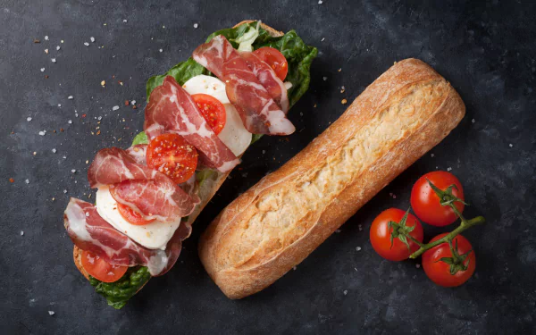 4K Ultra HD desktop wallpaper featuring a fresh sandwich with meat, tomato, and bread on a dark textured background alongside cherry tomatoes.
