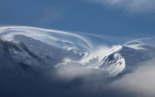 HD wallpaper of the snow-covered Alps during winter, showcasing stunning natural scenery with mist and a deep blue sky in the background.