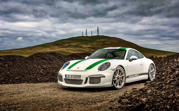 White Porsche 911 Turbo sports car with green racing stripes is parked on a rugged terrain under a cloudy sky in this 4K Ultra HD desktop wallpaper.