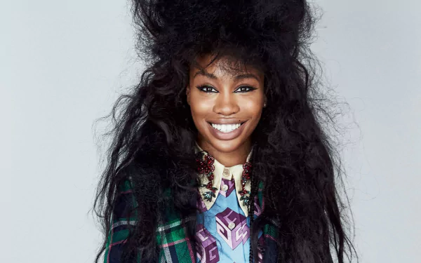 HD desktop wallpaper and background featuring SZA with a beaming smile and voluminous hair.