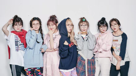 HD desktop wallpaper of seven smiling women in glasses with blonde and brunette hair, posing together in a colorful TV-show vibe inspired by Idol Drama Operation Team.