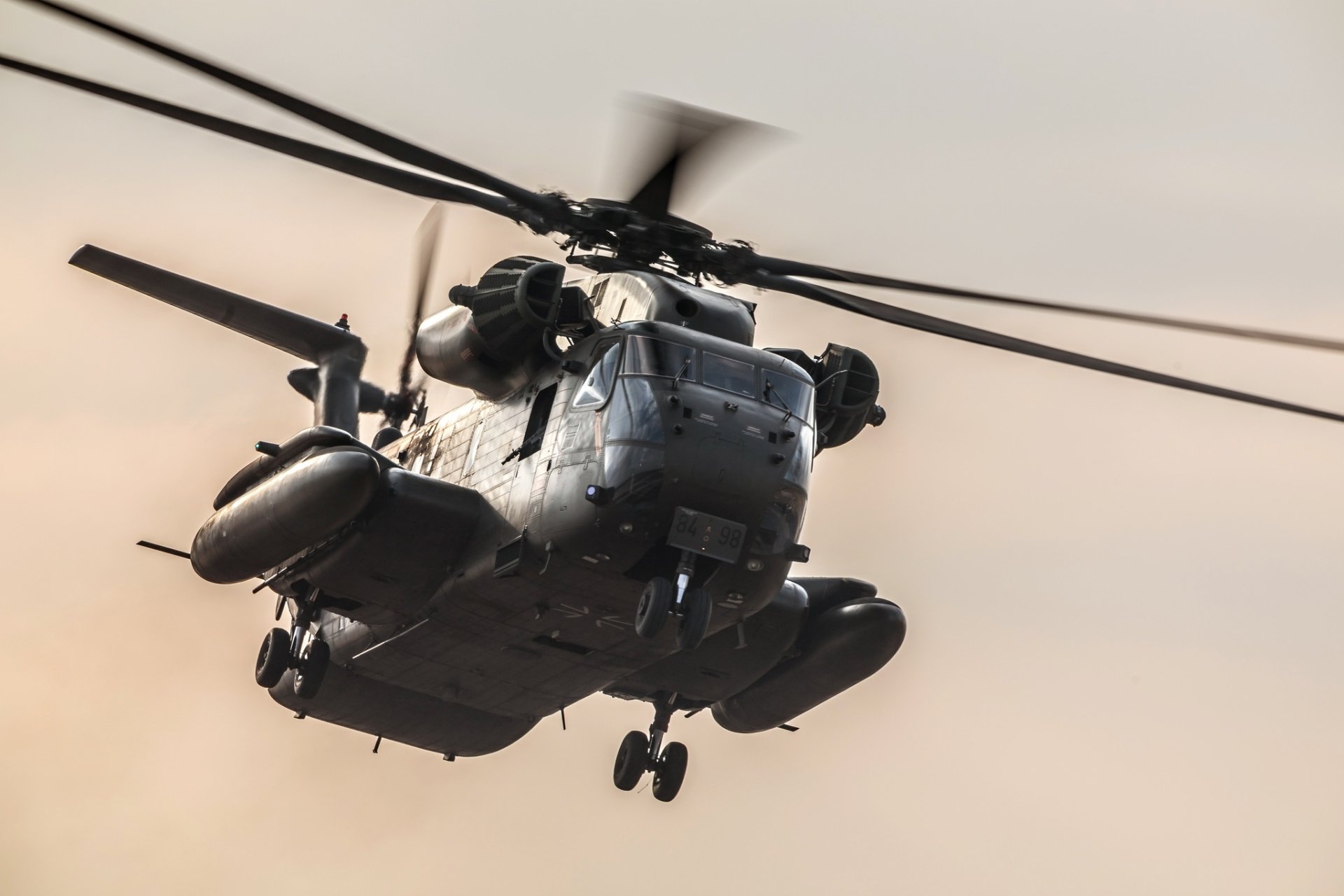 HD desktop wallpaper featuring a military Sikorsky CH-53 Sea Stallion transport helicopter in flight against a soft, neutral sky background.