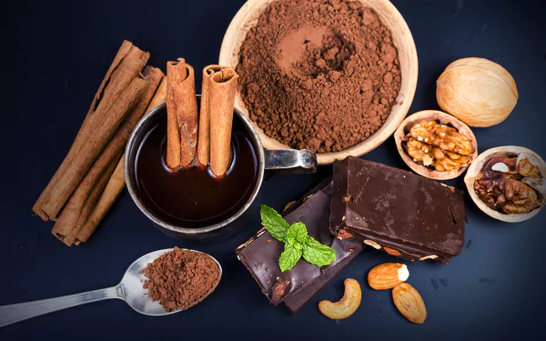 HD desktop wallpaper of a still life with chocolate, cinnamon sticks, cocoa powder, nuts, and a chocolate drink arranged on a dark background.