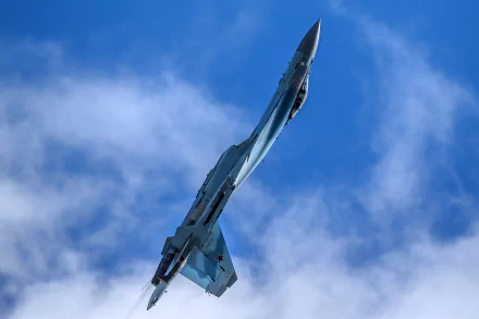 A Sukhoi Su-35 military jet fighter soars vertically against a bright blue sky with scattered clouds in this HD warplane desktop wallpaper.