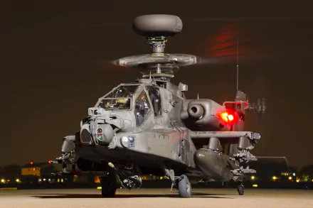 HD desktop wallpaper featuring a Boeing AH-64 Apache attack helicopter on a runway at night, highlighting its military design and advanced aircraft features.
