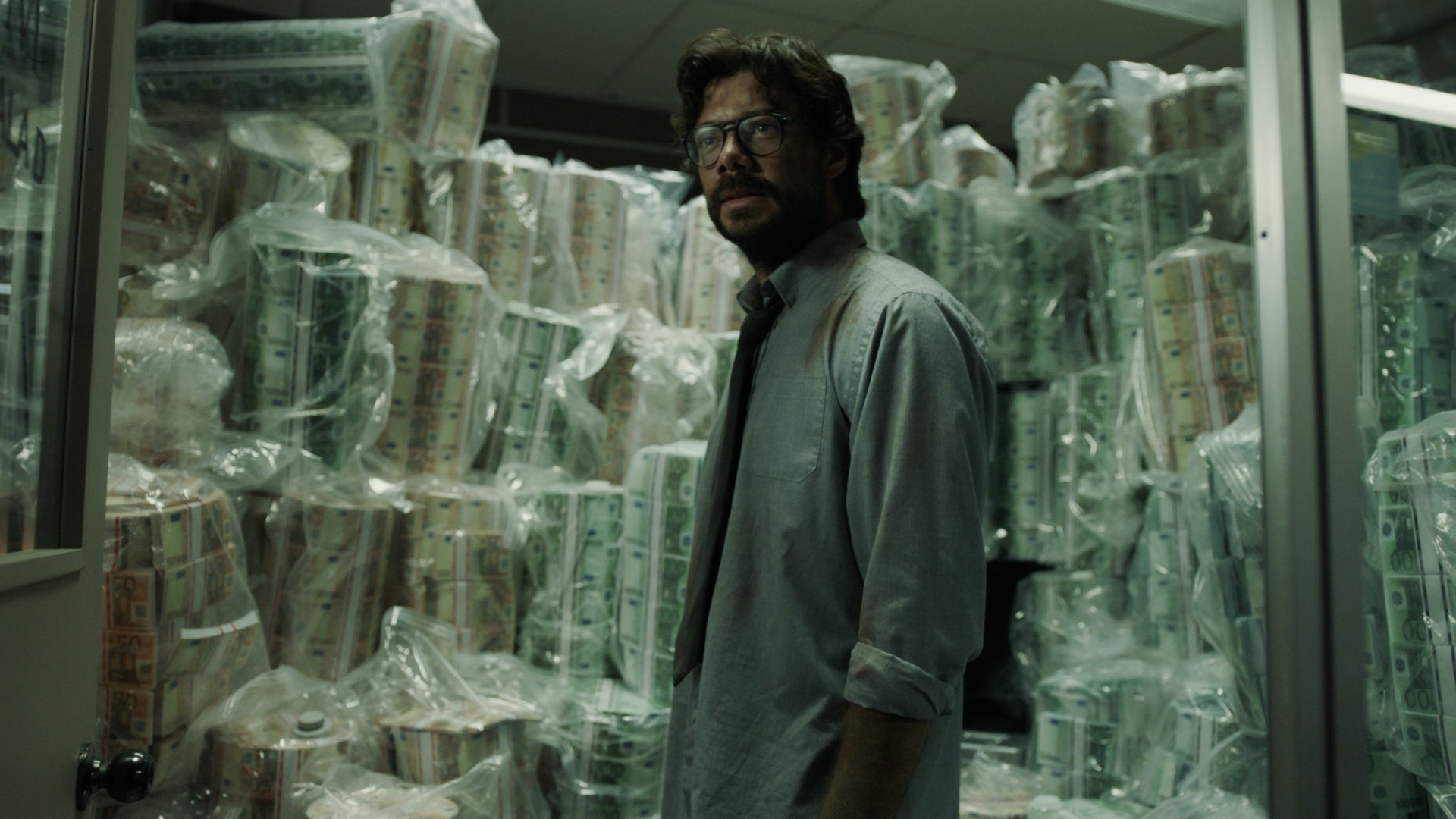 Moody 2K Quad HD PC desktop wallpaper of a man in a shirt and tie standing among stacks of wrapped cash in a dim vault — TV Show Money Heist background.