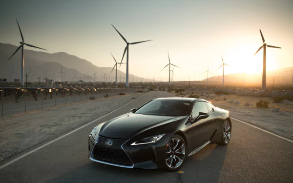 Black Lexus LC 500 on a desert road at sunrise, flanked by wind turbines; HD PC desktop wallpaper showing a luxury car and renewable-energy landscape.
