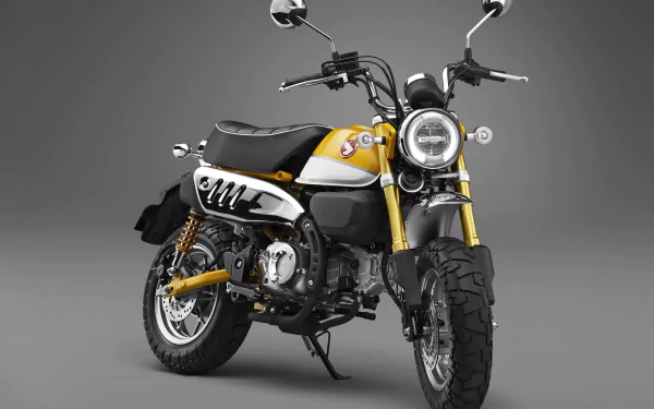 4K Ultra HD wallpaper of a yellow and black Honda Monkey motorcycle against a gray background, highlighting its compact and stylish design.