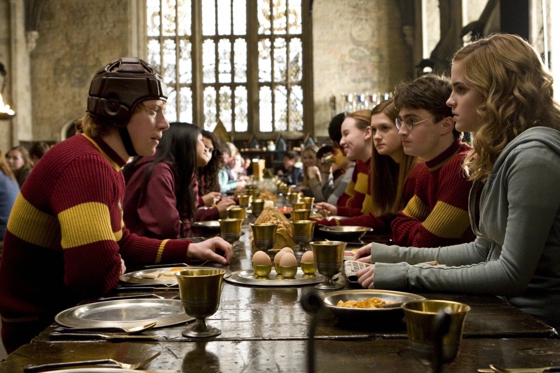 HD desktop wallpaper featuring Hermione Granger, Harry Potter, and Ron Weasley in the Hogwarts Great Hall from the movie Harry Potter and the Half-Blood Prince.