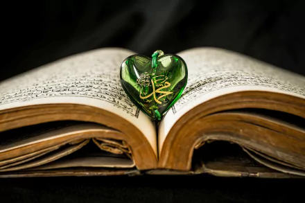 Open Holy Book of Kurane Kerim with a green heart-shaped ornament bearing Arabic calligraphy, framed as a 5K Ultra HD PC desktop wallpaper and background.