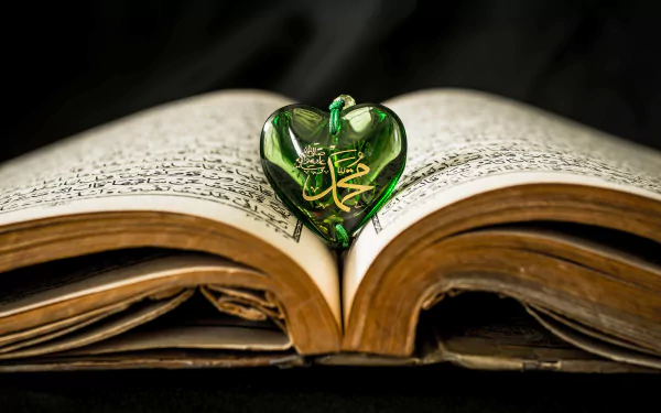 Open Holy Book of Kurane Kerim with a green heart-shaped ornament bearing Arabic calligraphy, framed as a 5K Ultra HD PC desktop wallpaper and background.